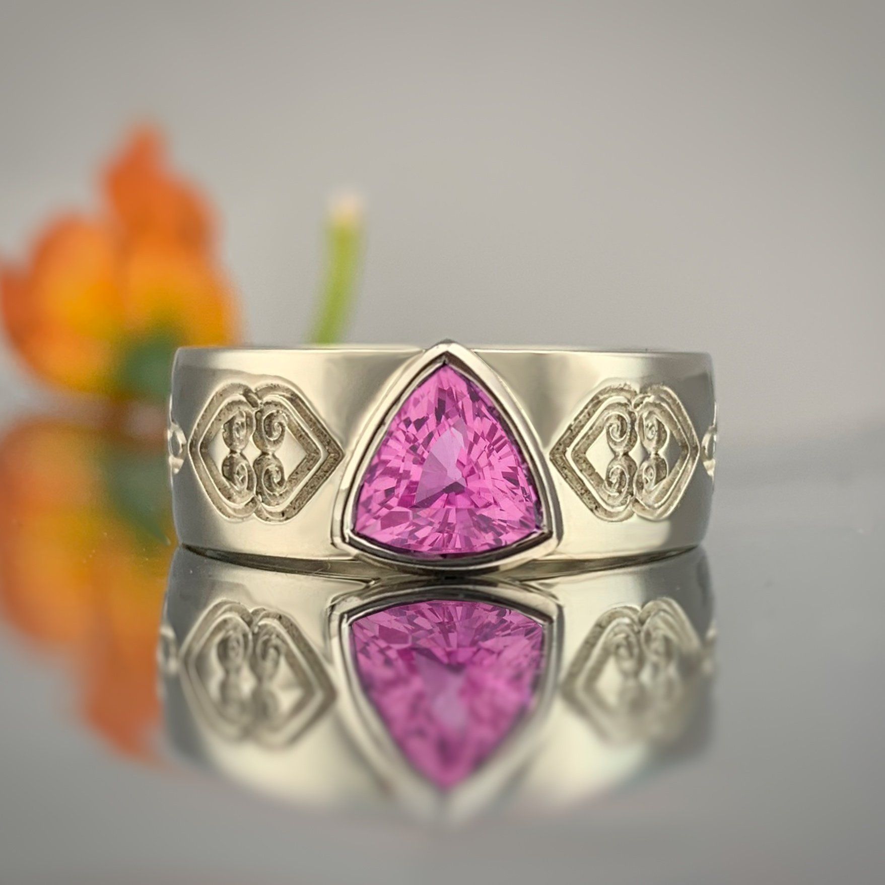 A white gold ring with a pink stone in the center