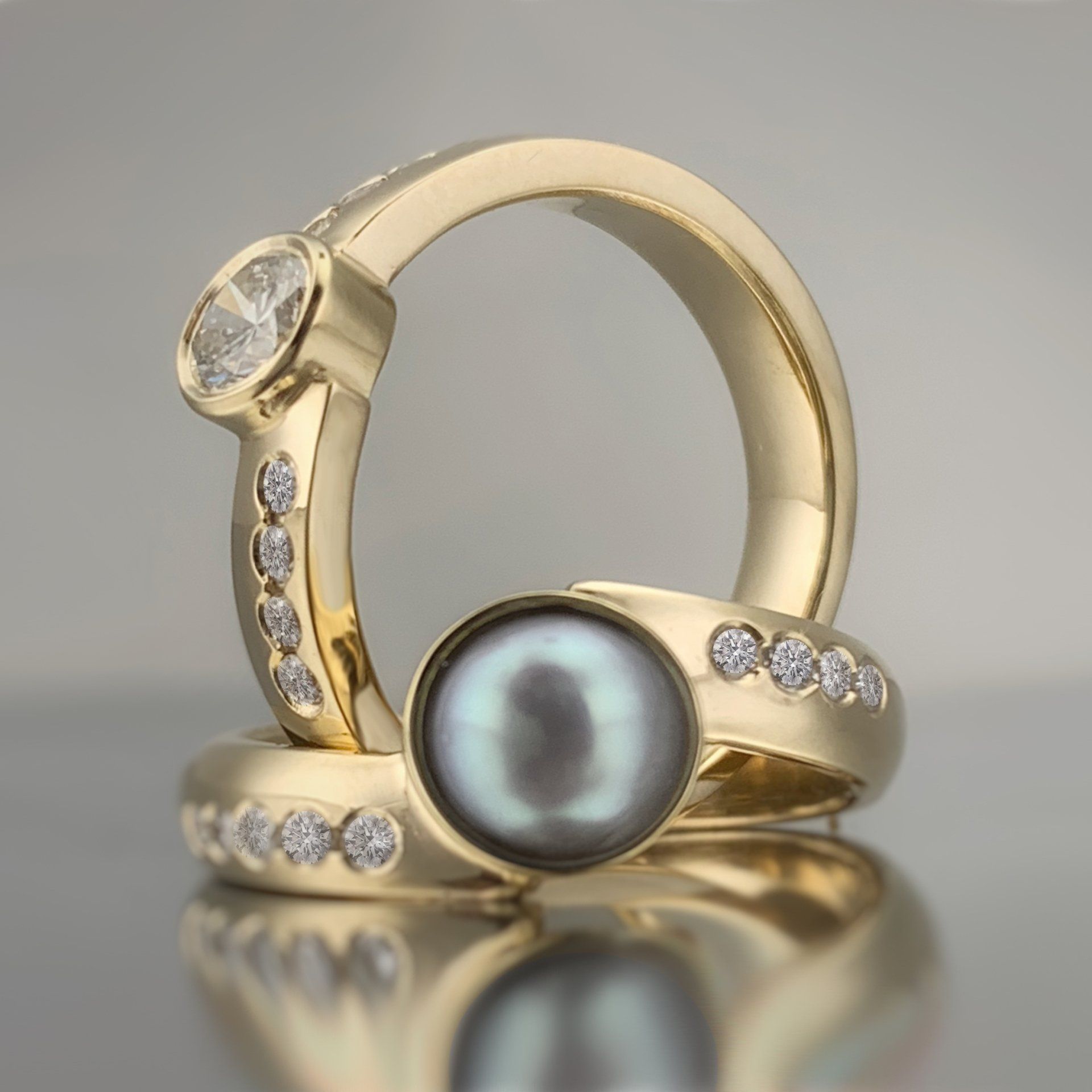 Two gold rings with a black pearl and diamonds