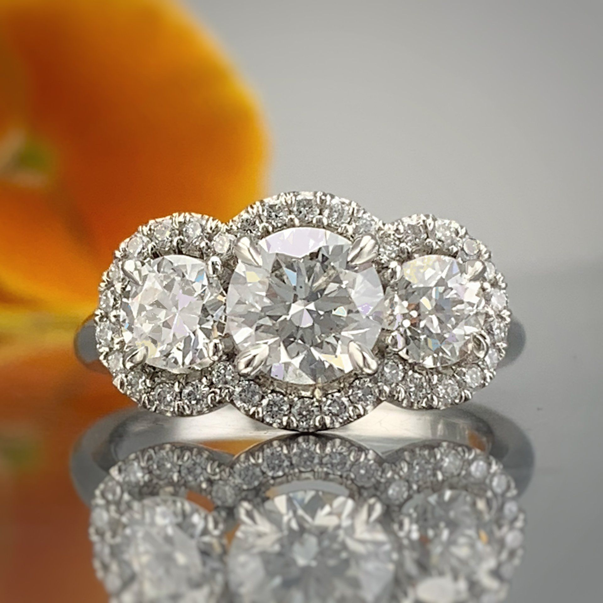 A close up of a diamond ring with a flower in the background