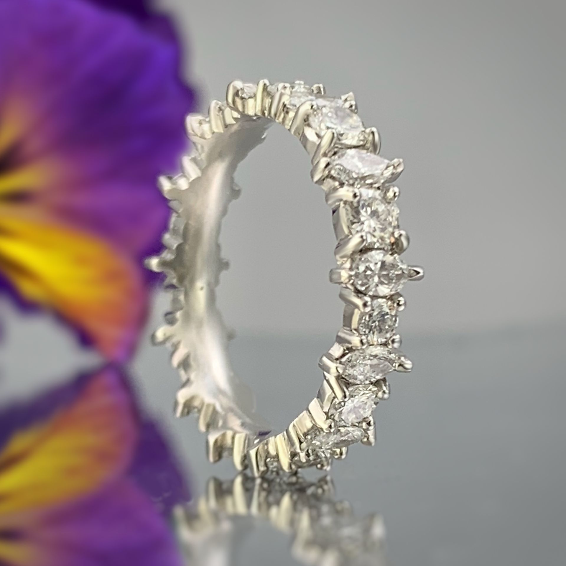 A silver ring with a purple flower in the background