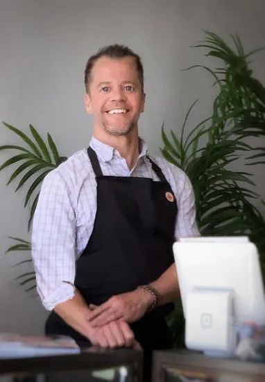 A man wearing a plaid shirt and an apron with a butterfly on it