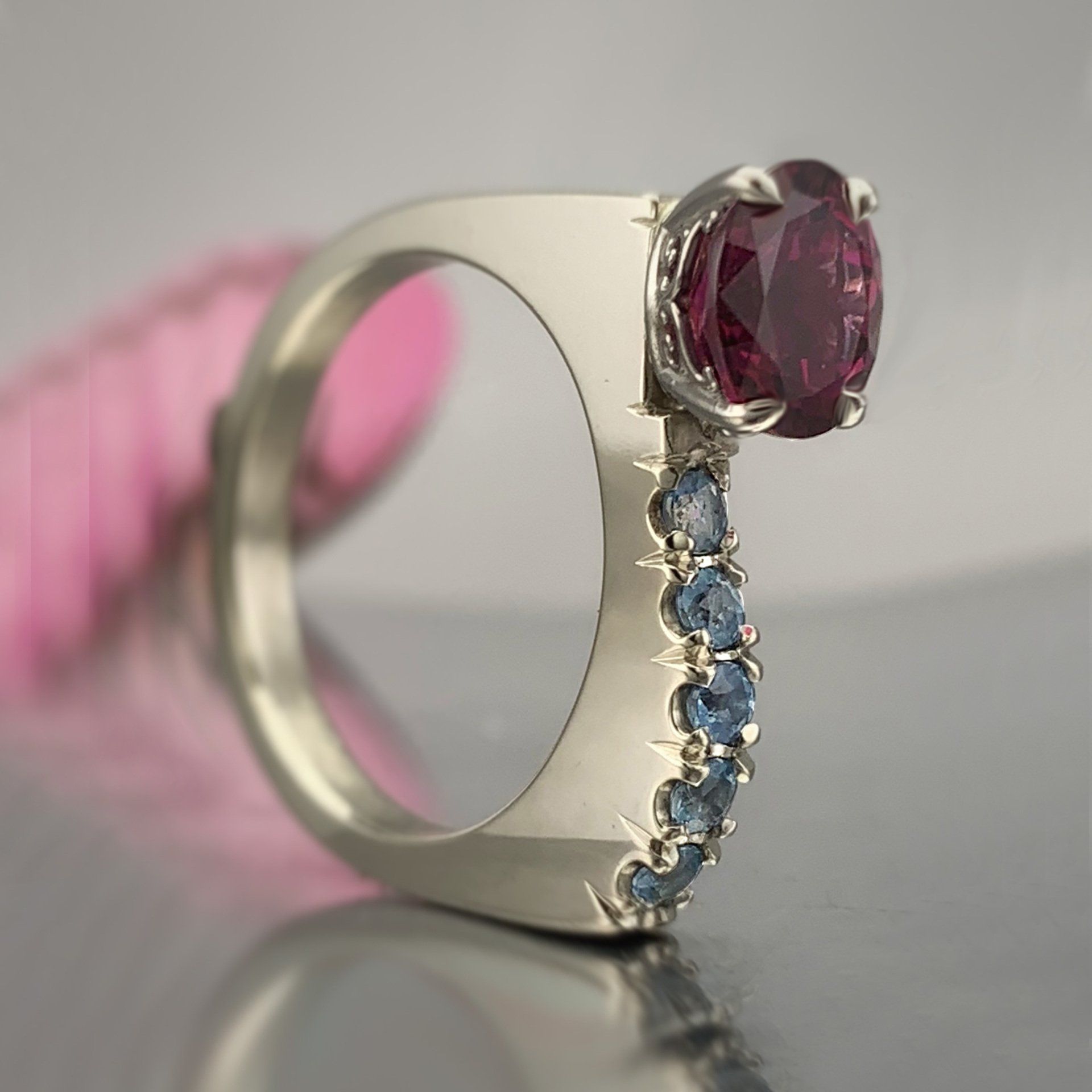 A silver ring with a red stone and blue stones