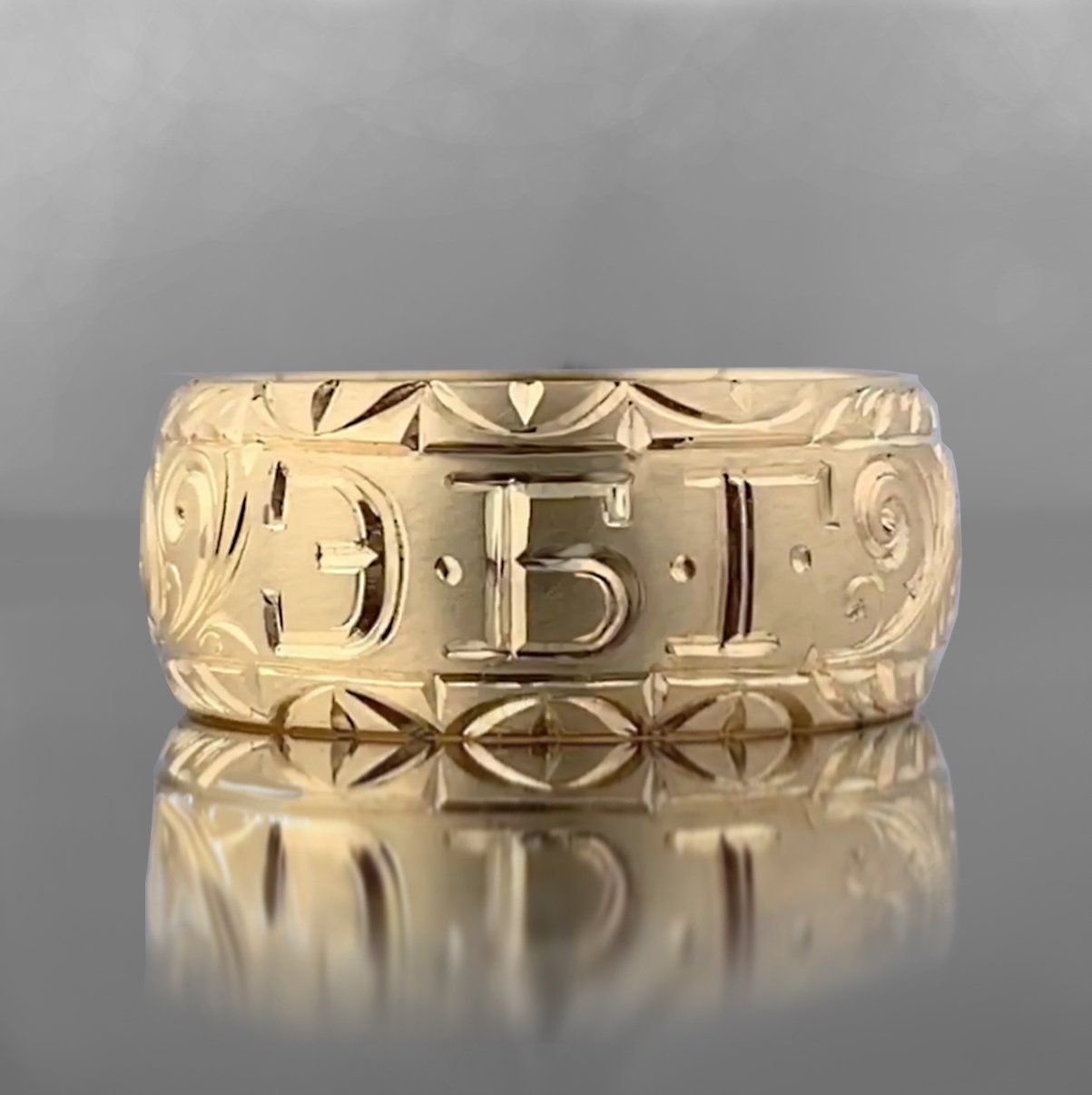 A close up of a gold ring with a reflection on a table.