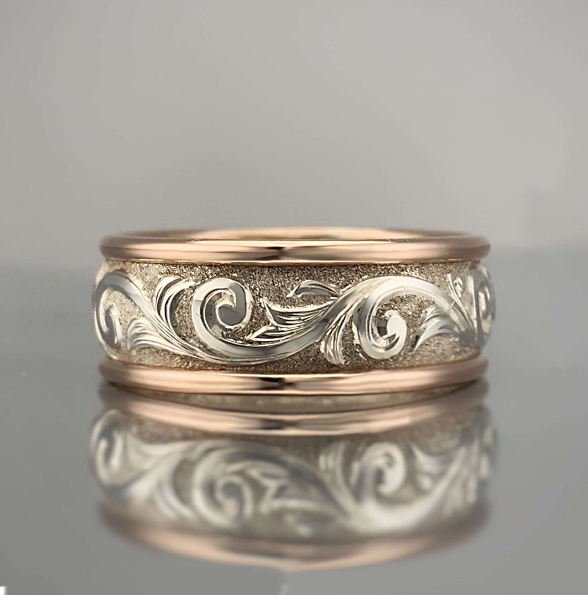 A gold and silver ring with a pattern on it is sitting on a table.