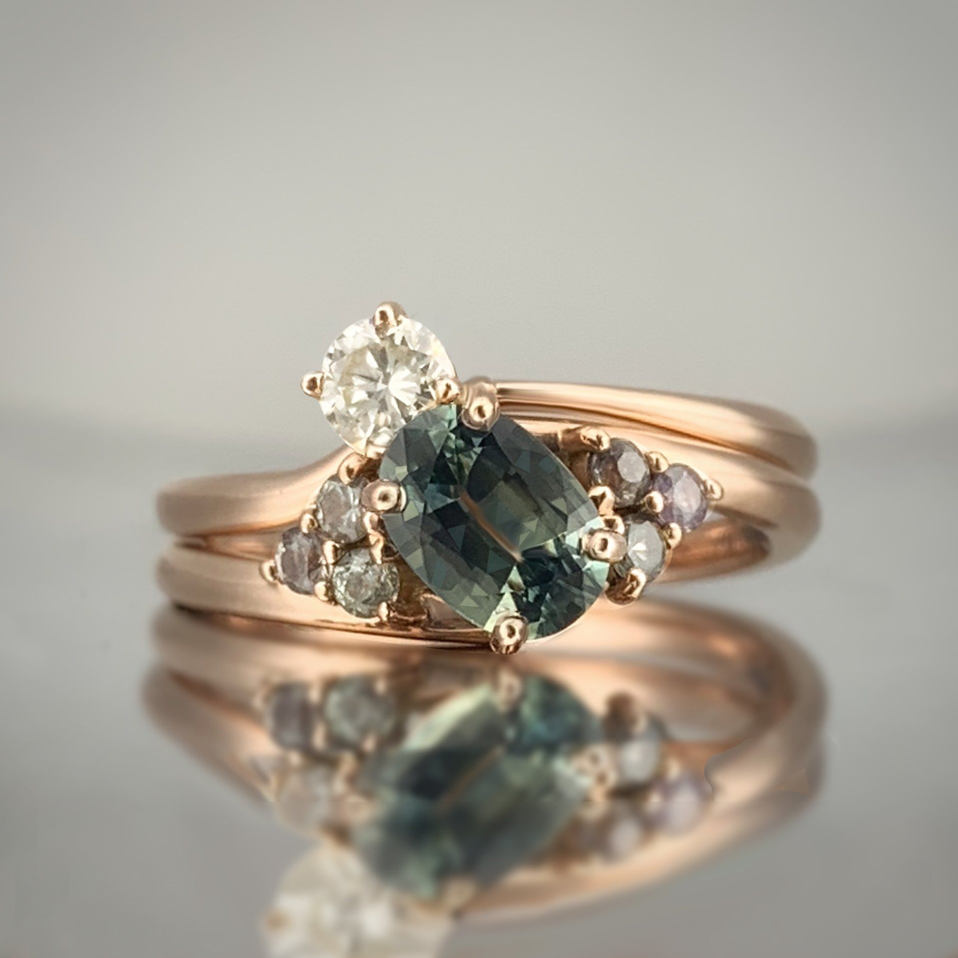 A close up of a ring with a green stone and diamonds on a table.