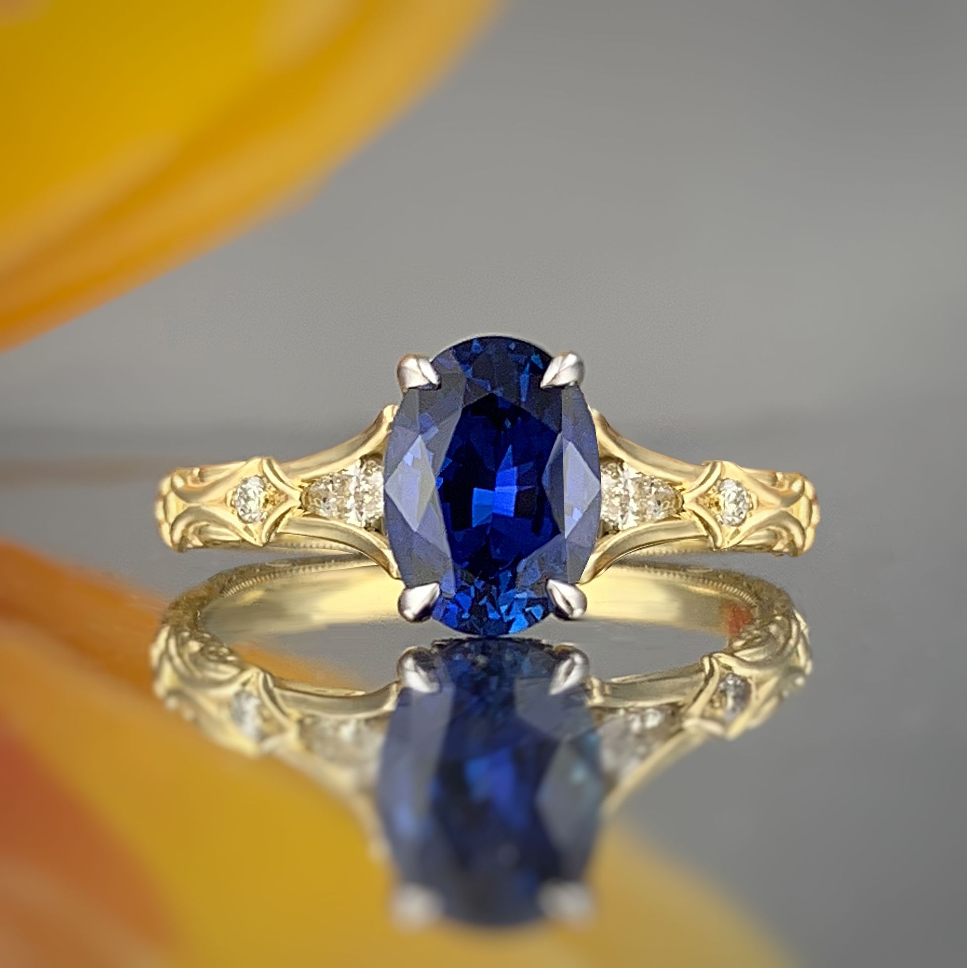 A close up of a sapphire and diamond ring on a table.