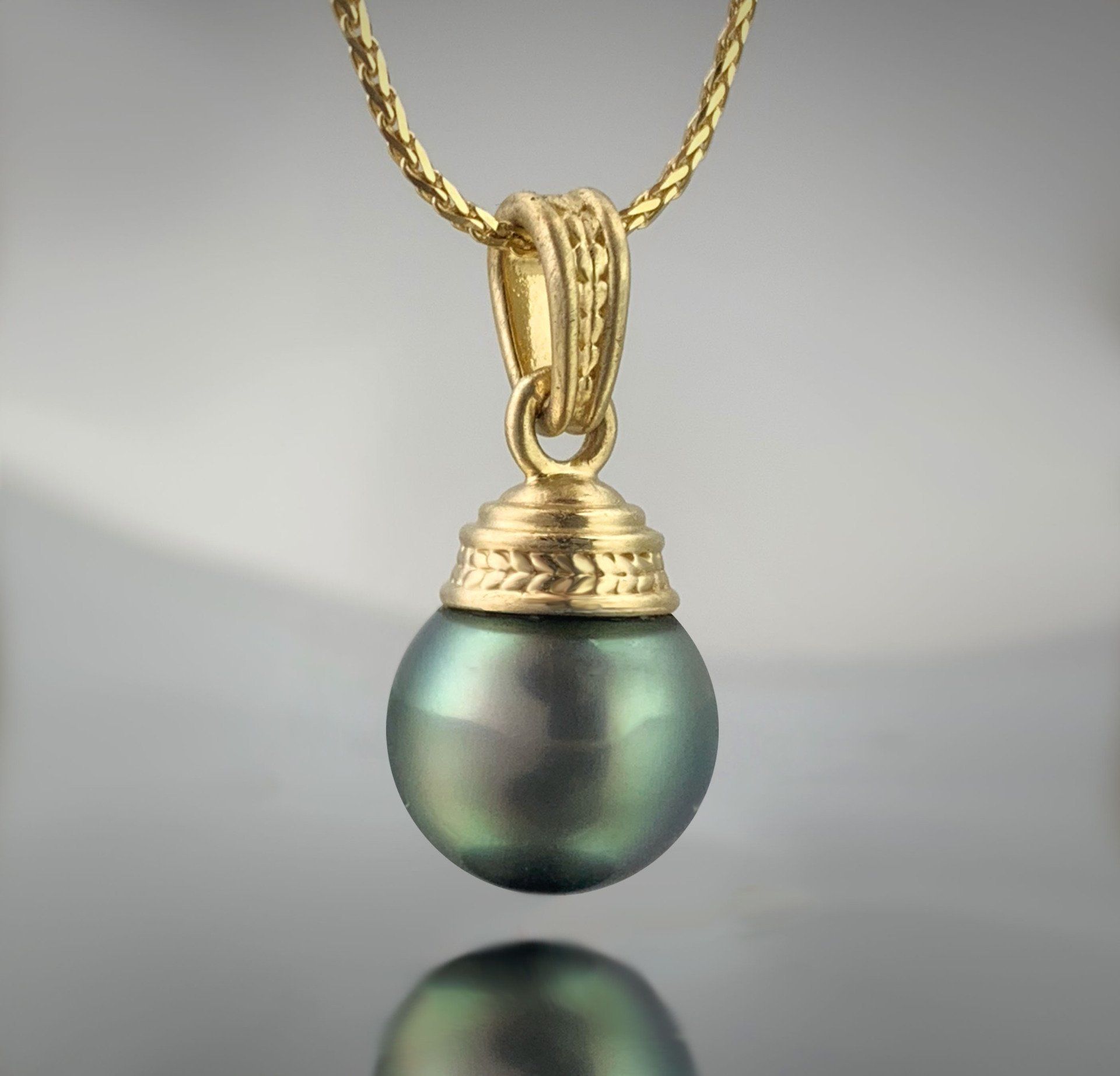 A pendant with a green pearl on a gold chain