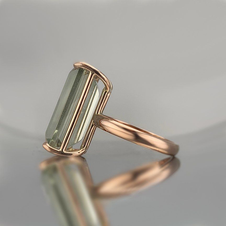 A rose gold ring with a green stone in the center