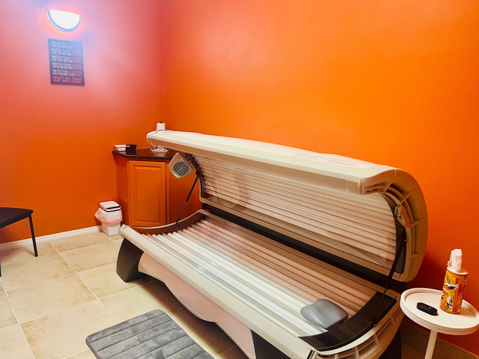 Orange tanning bed booth in a room with bright orange walls and a small side table