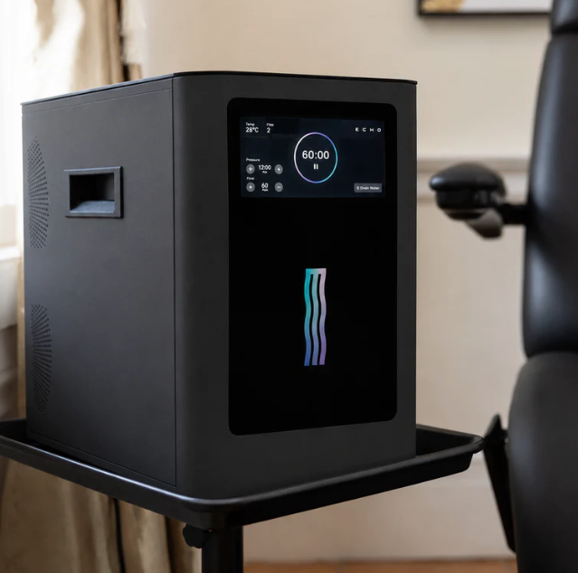 Black desktop appliance with a small digital display on a side table in an office chair setting