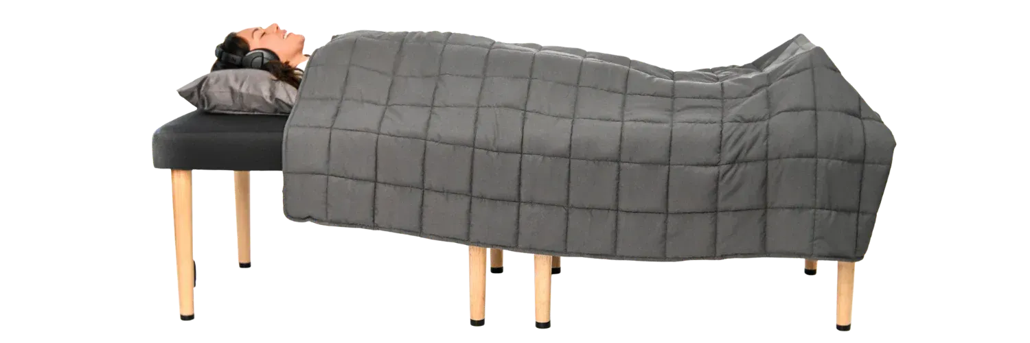 Person lying on a massage table covered with a gray blanket