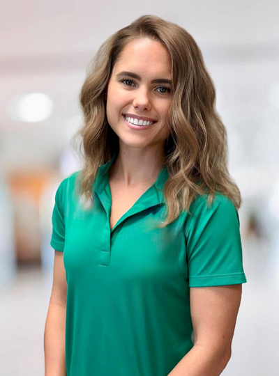 Smiling woman in a green polo shirt standing in a bright indoor setting