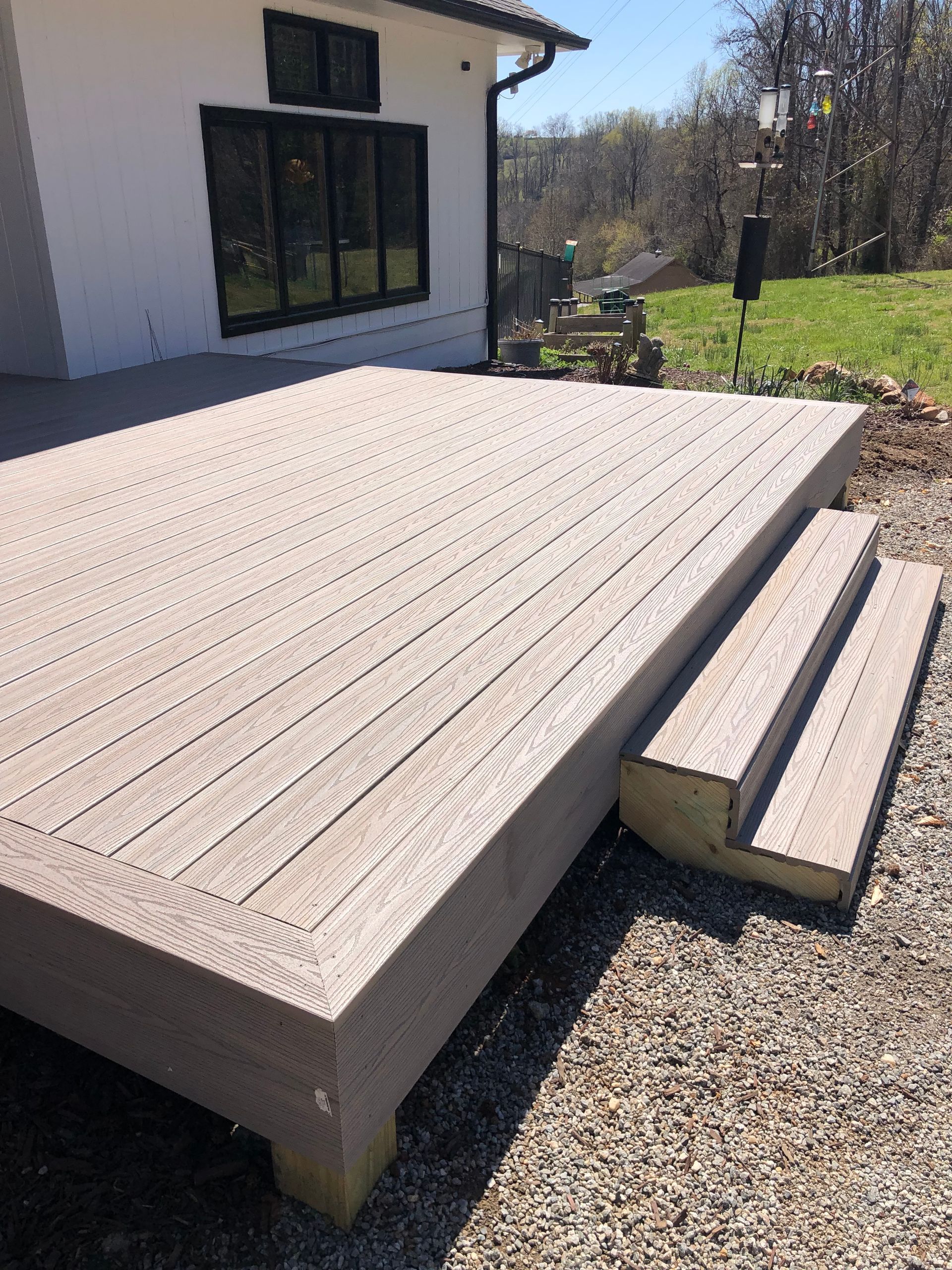 A wooden deck with stairs and a white house in the background.