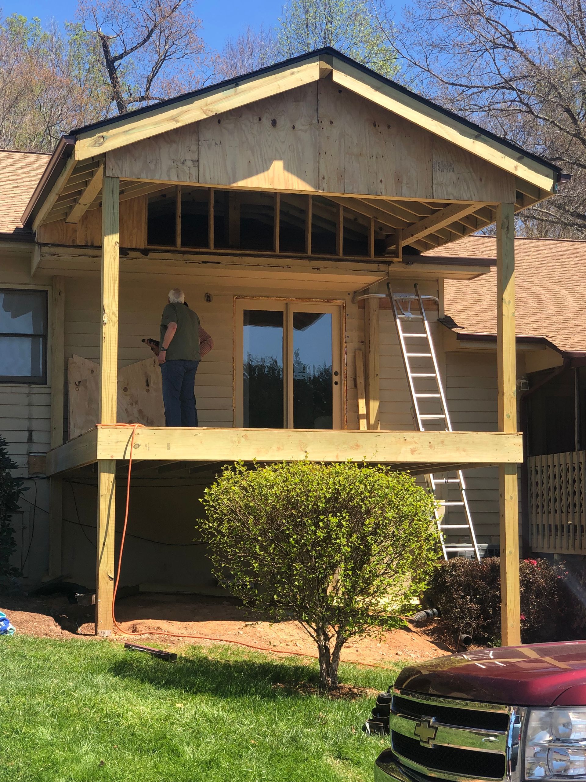 A man is standing on the porch of a house under construction.