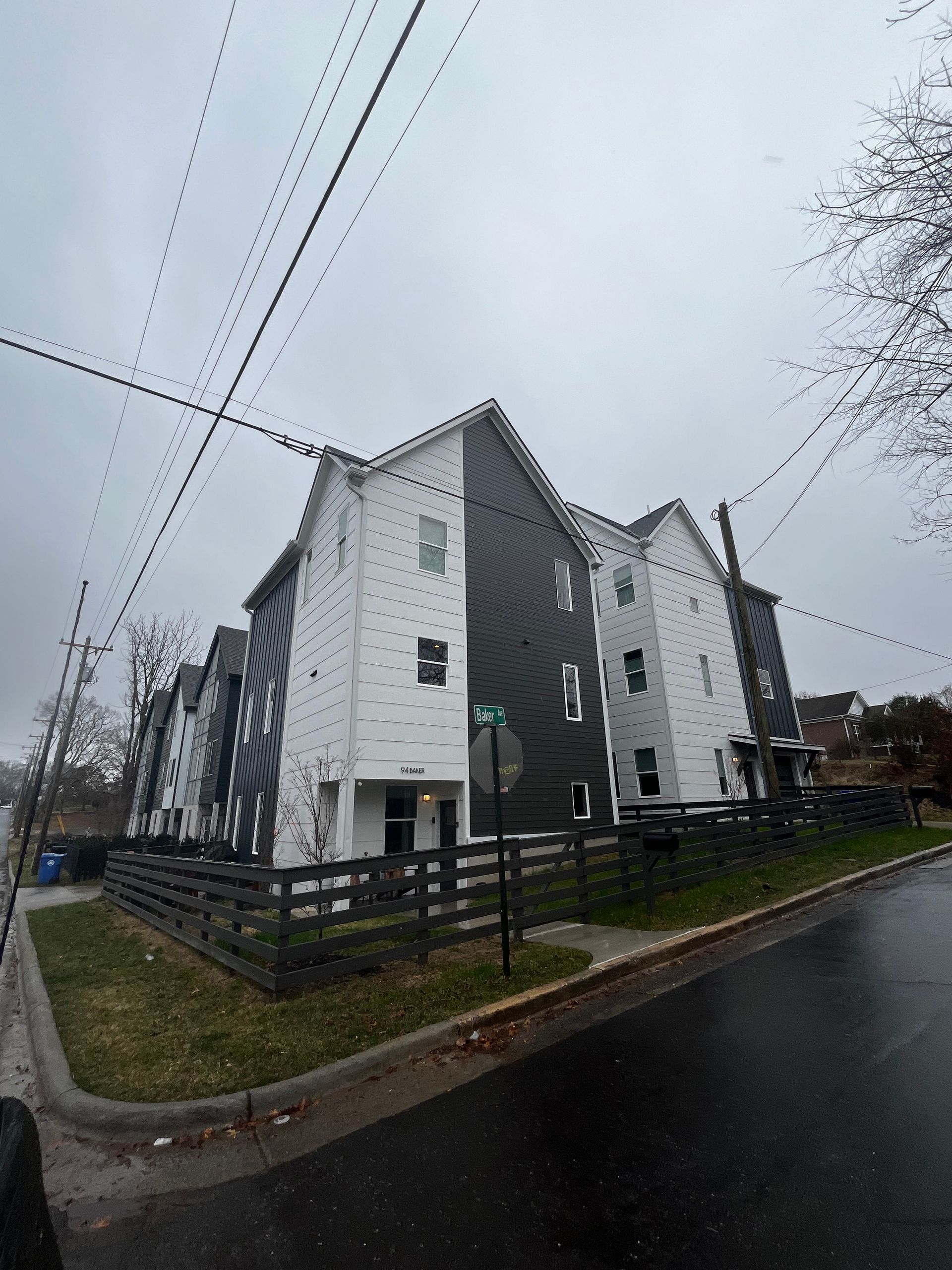 A large apartment building with a fence in front of it on a cloudy day.