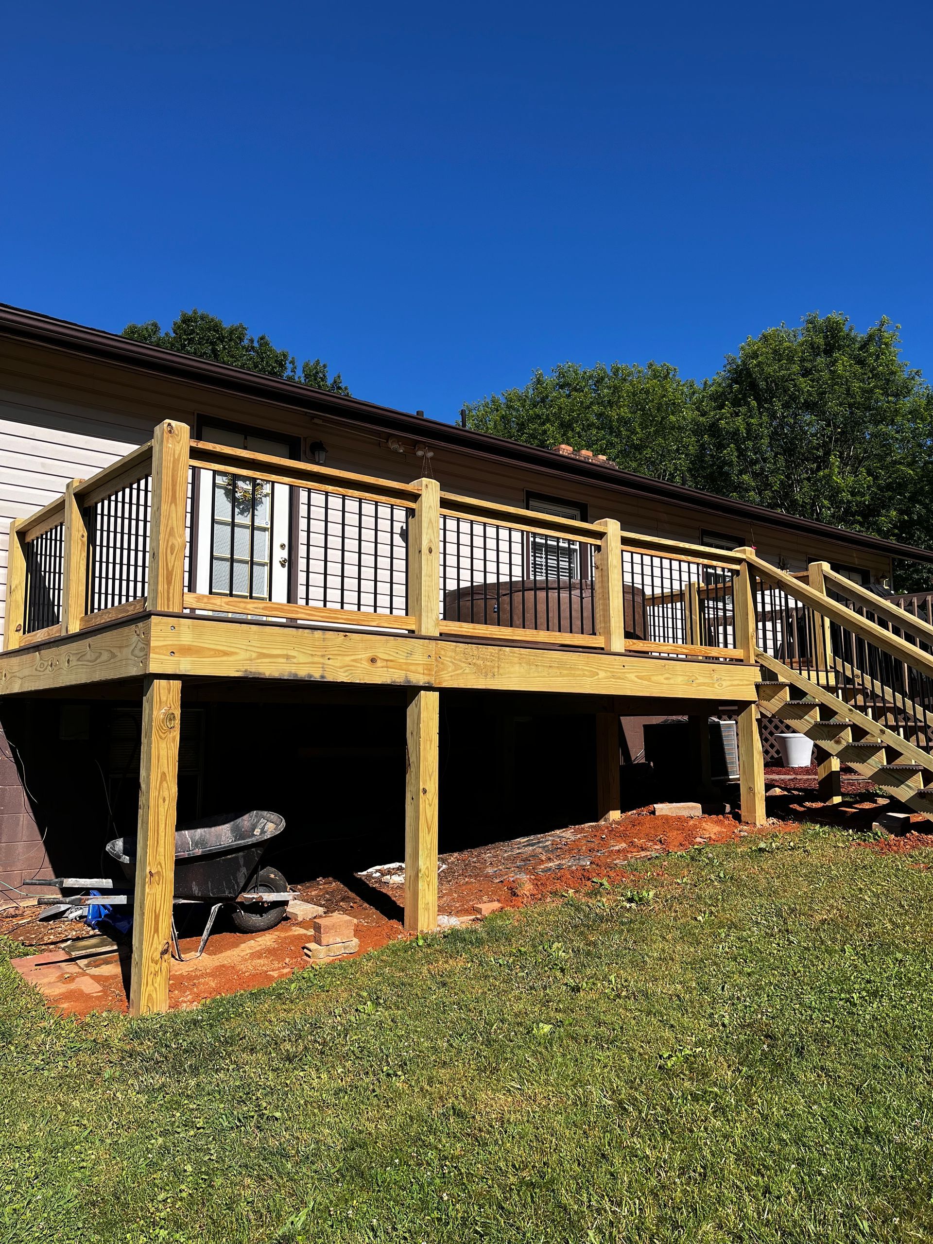 A wooden deck with stairs leading up to it is in front of a house.