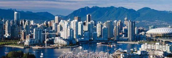 Serving Vancouver BC City skyline with tall buildings, harbor water, and mountains under a clear blue sky