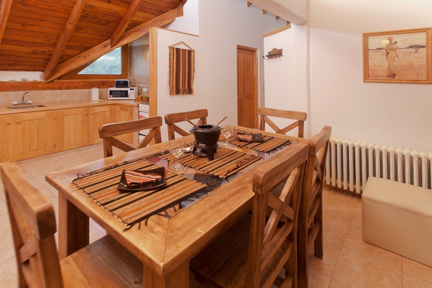 Acogedor comedor de madera con mesa, escalera y radiador en un interior rústico tipo loft.