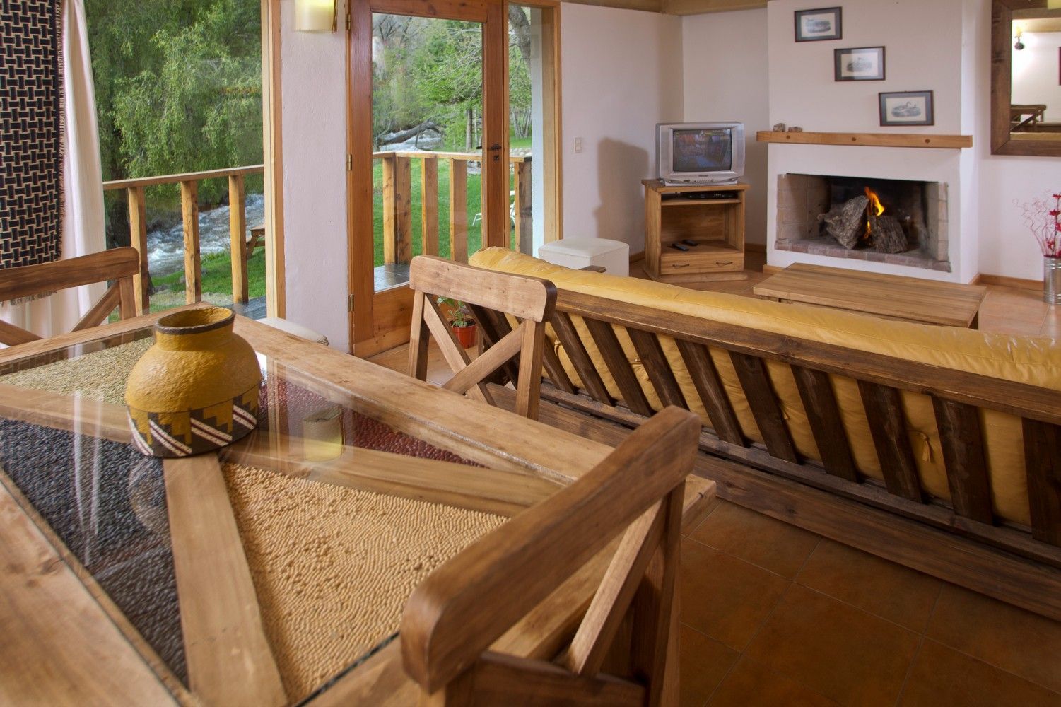 Acogedora sala de estar con muebles de mimbre, televisor, chimenea y puertas correderas que dan a un balcón.