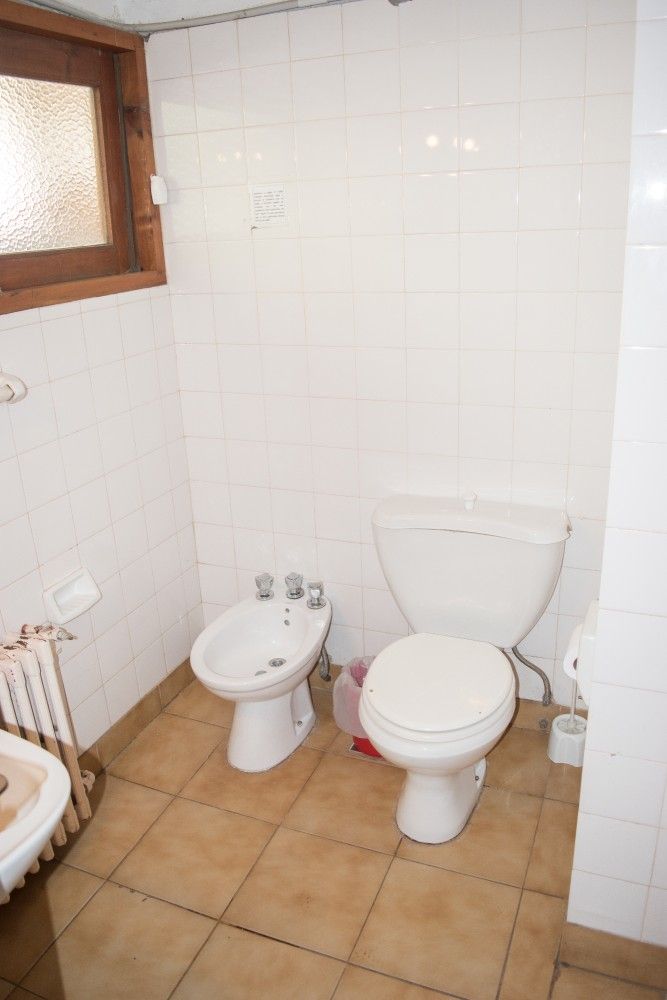 Baño pequeño con azulejos, inodoro, bidé, lavabo y ventana esmerilada.