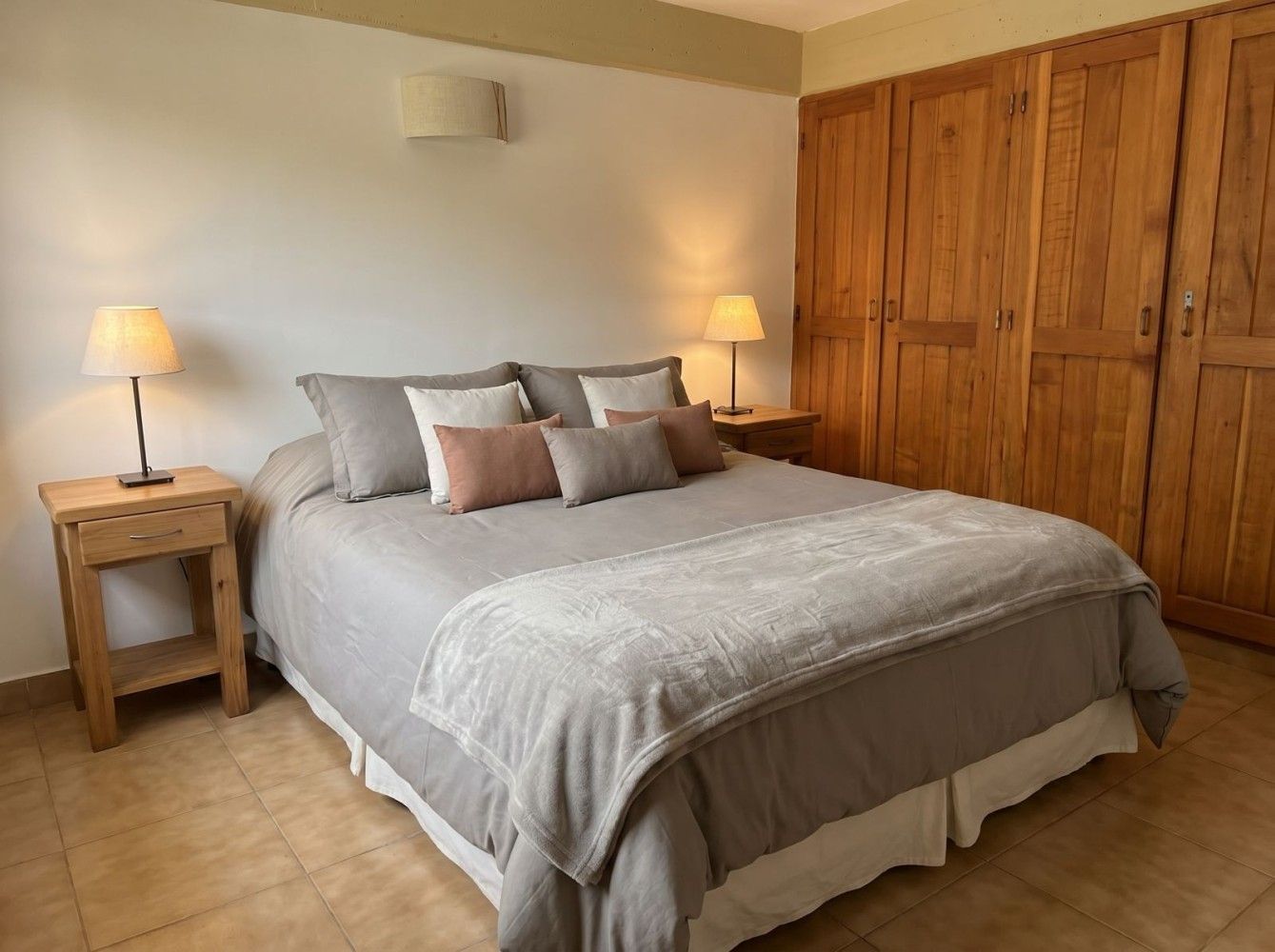 Habitación acogedora con cama, lámparas de mesilla y puertas de armario de madera.