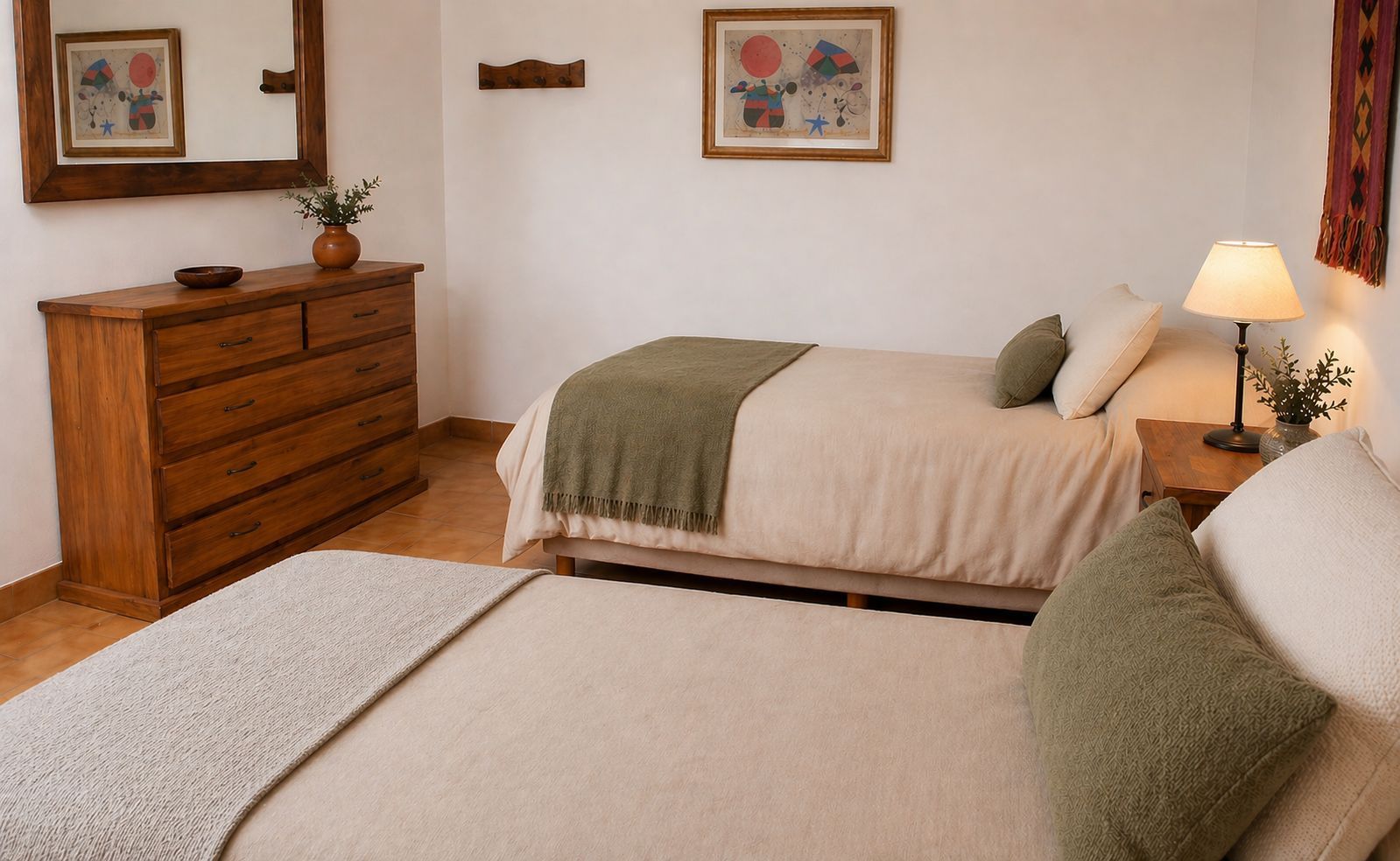 Acogedora habitación con dos camas, cómoda de madera, lámpara, cuadro enmarcado y decoración neutra.