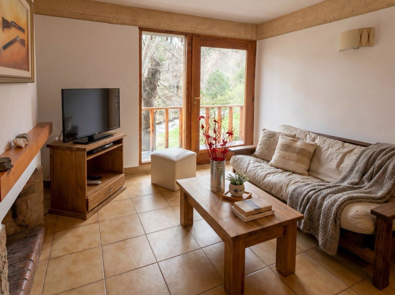 Luminoso salón con sofá, mesa de centro, televisor y puertas que dan al balcón y dejan entrar la luz natural.