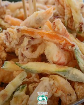 Primo piano di strisce di verdure fritte e croccanti su un piatto, dorate con i bordi verdi.