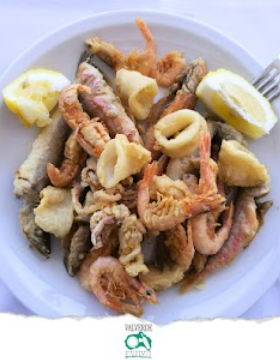 Piatto di frutti di mare fritti con spicchi di limone su un piatto bianco