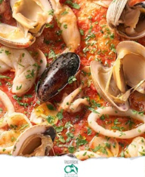 Pasta ai frutti di mare con vongole e una cozza in salsa di pomodoro, guarnita con prezzemolo.