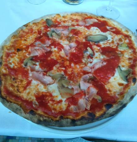 Pizza al formaggio con salsa di pomodoro e basilico su una tovaglia bianca, vista dall'alto.