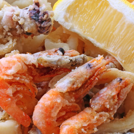 Gamberi e calamari fritti con uno spicchio di limone su un piatto
