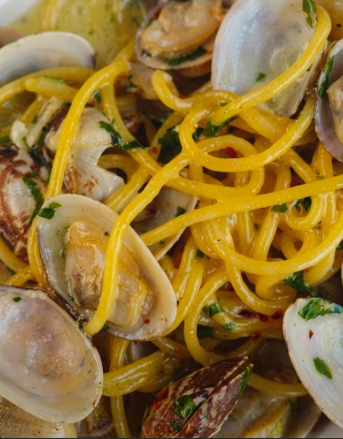 Spaghetti alle vongole in un sugo leggero, guarniti con erbe aromatiche e scorza di limone.