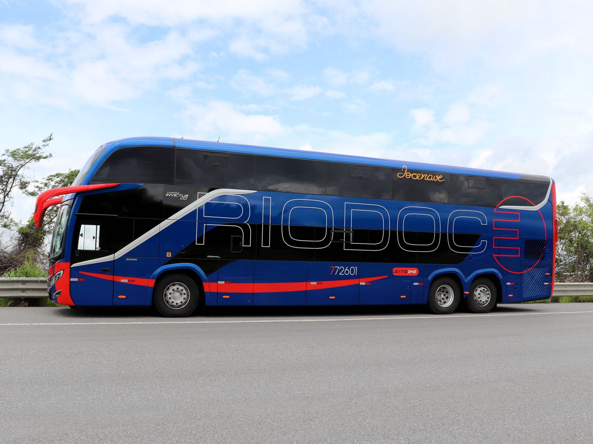 Um ônibus de passageiros Riodoce azul de dois andares estacionado na beira da estrada contra um fundo de céu.