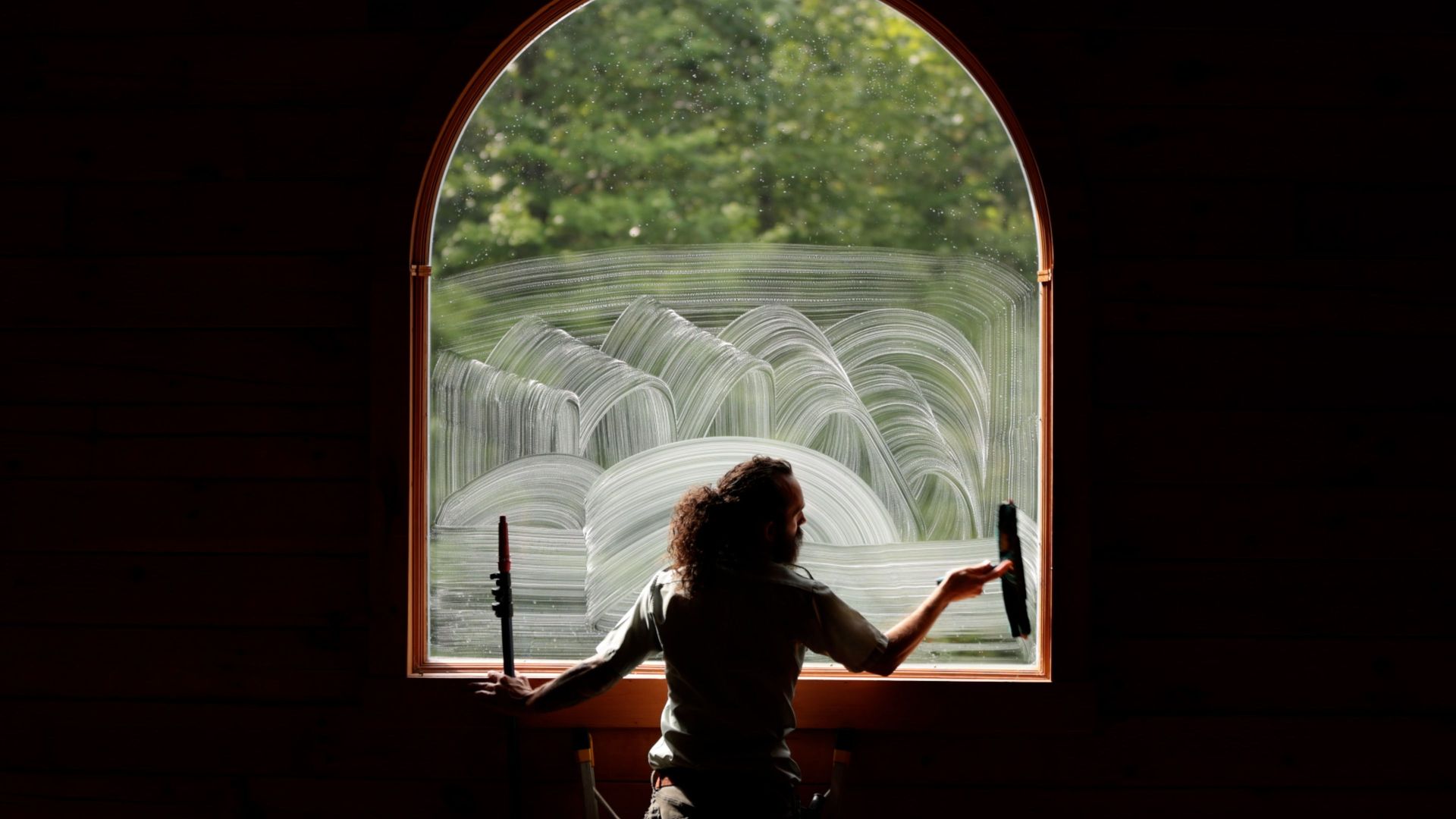 A woman is cleaning a window with a squeegee.