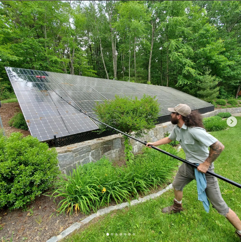 A man is cleaning a solar panel with a brush.