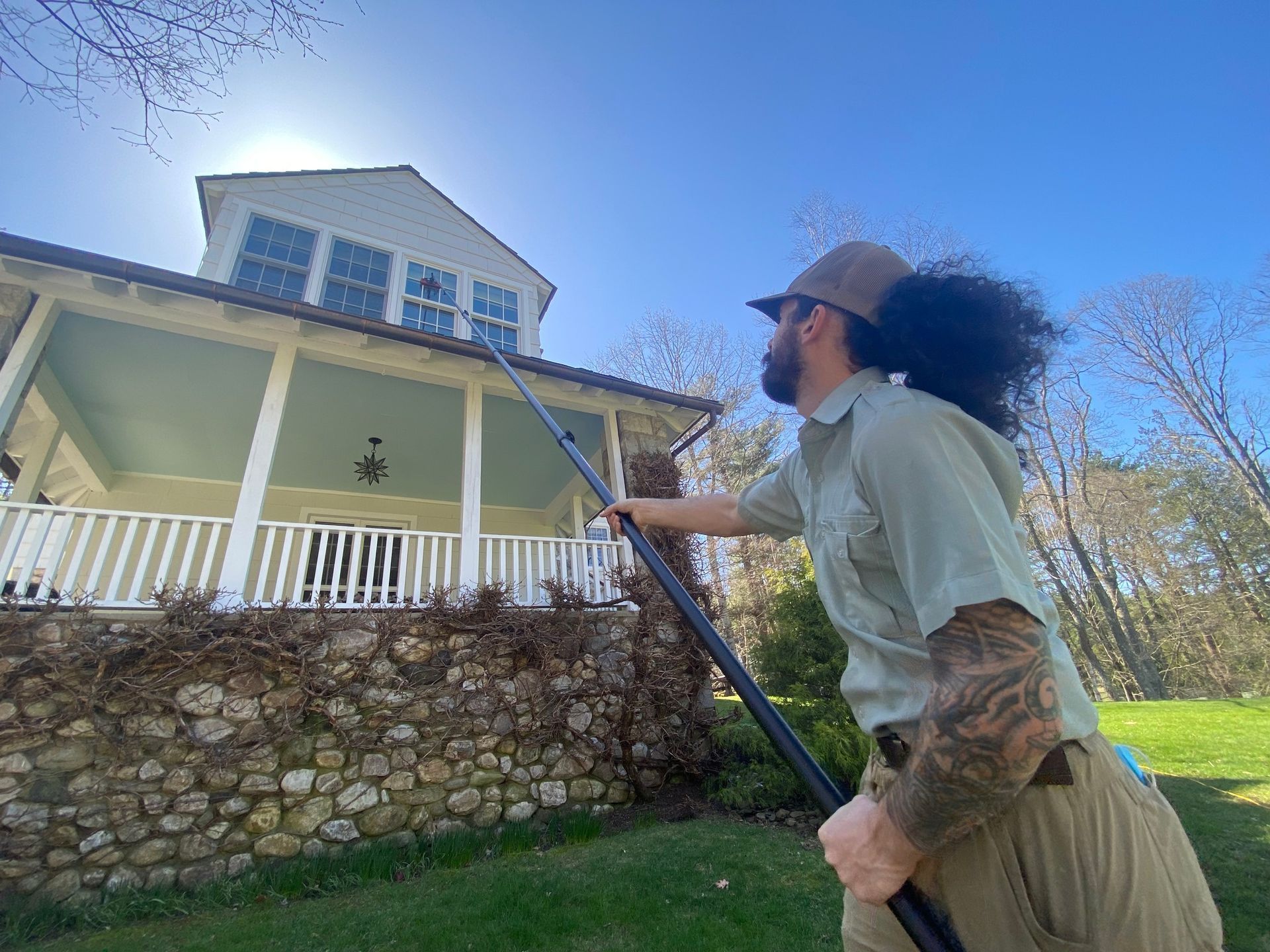 A man is cleaning the roof of a house with a hose.