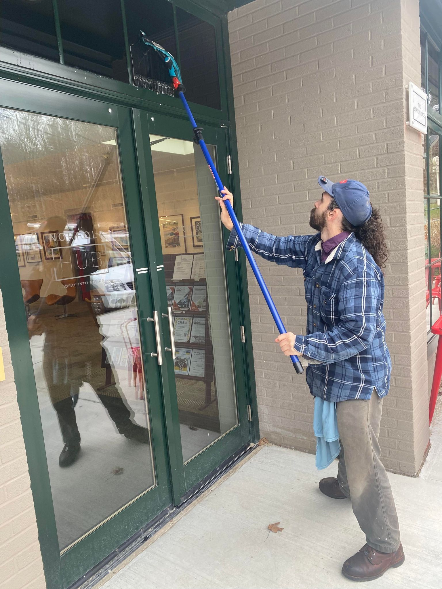 A man is cleaning a glass door with a mop.