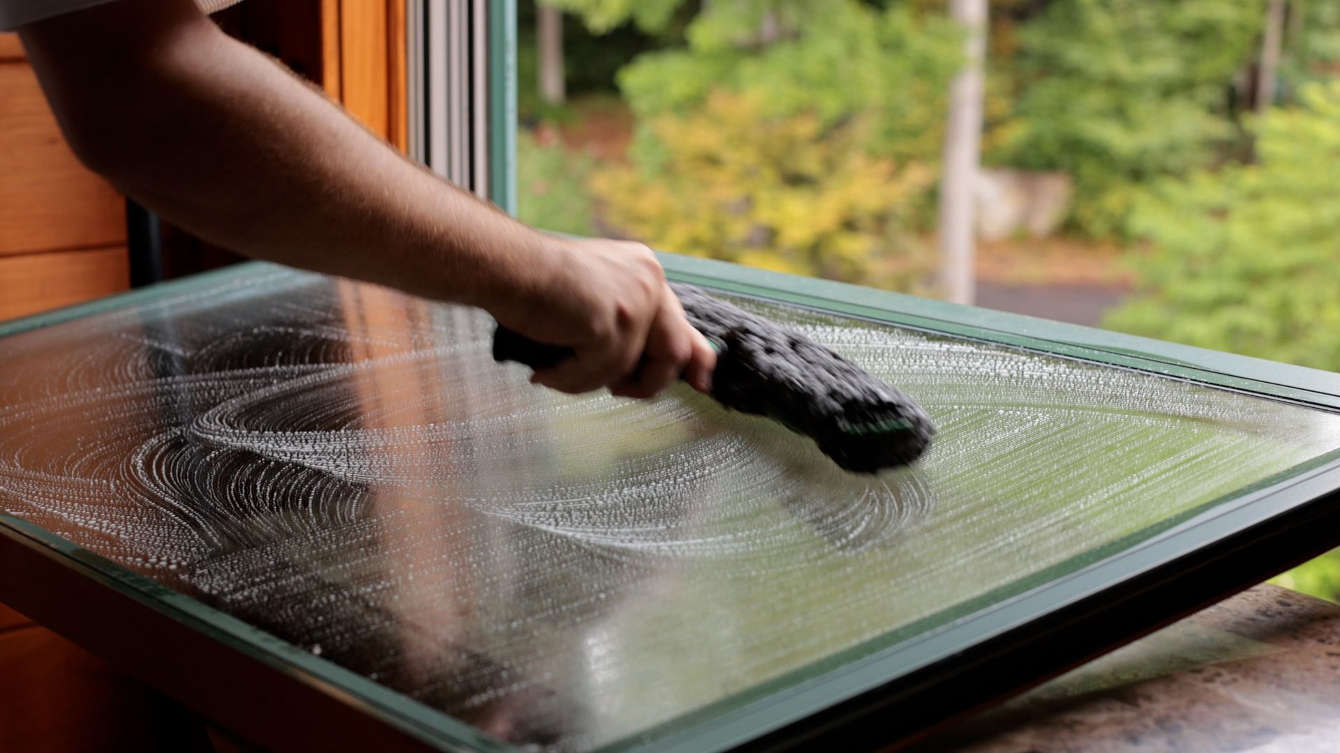 A person is cleaning a window with a brush.
