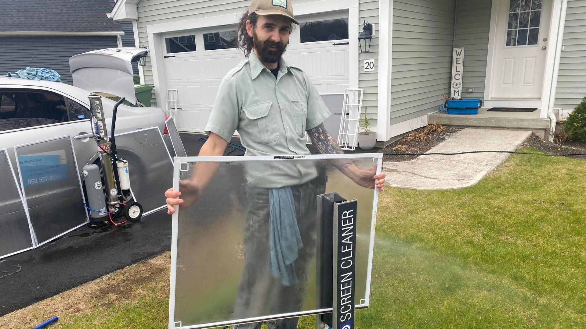 A man is holding a screen door in front of a house.