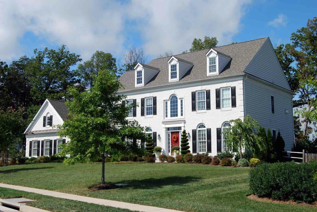 A large white house with black shutters and a red door