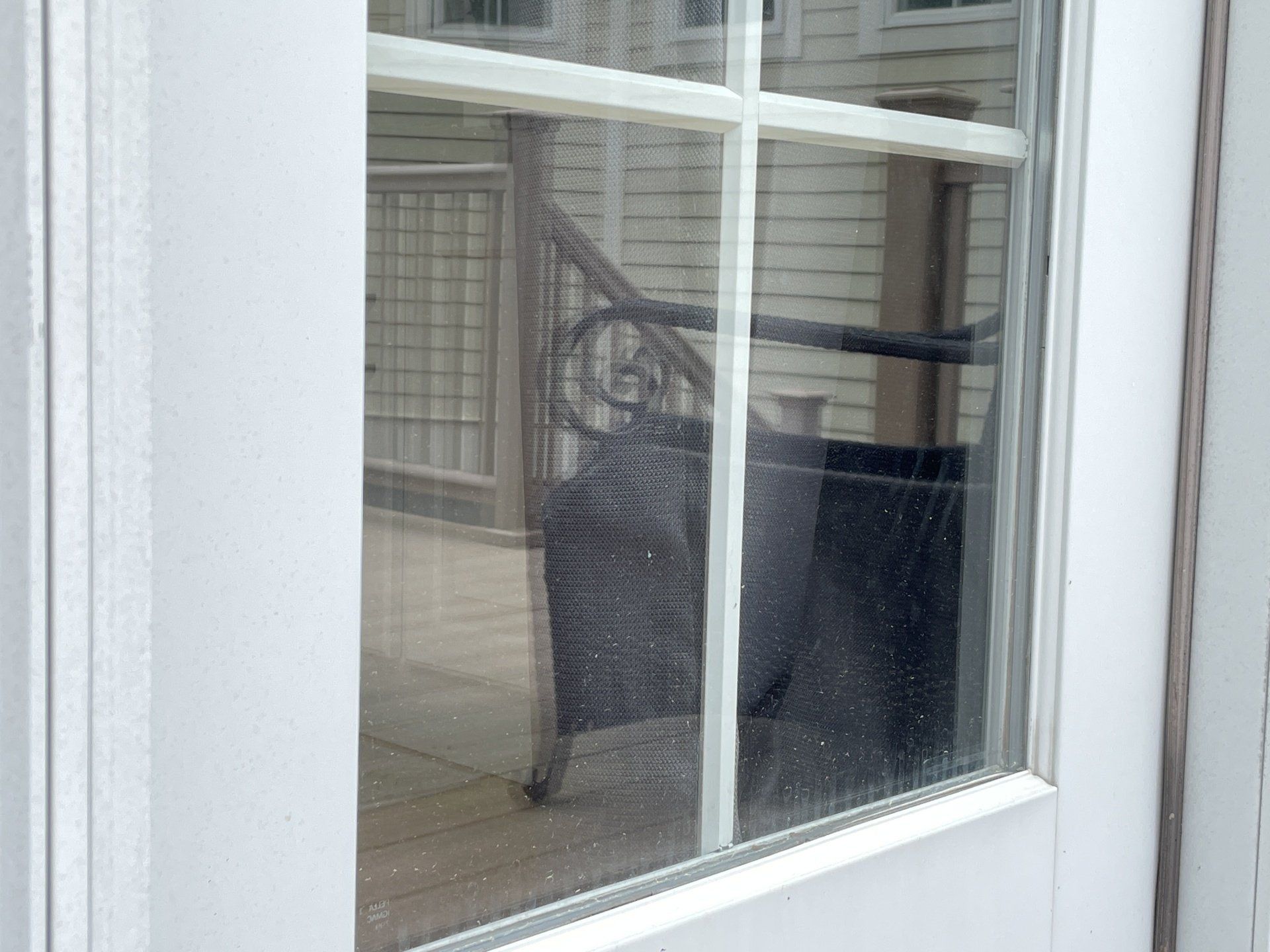 A white door with a reflection of a chair in the window