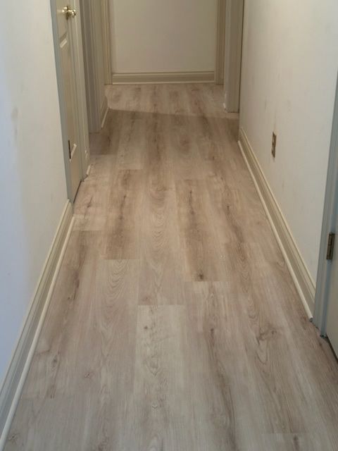A hallway with a wooden floor and white walls.