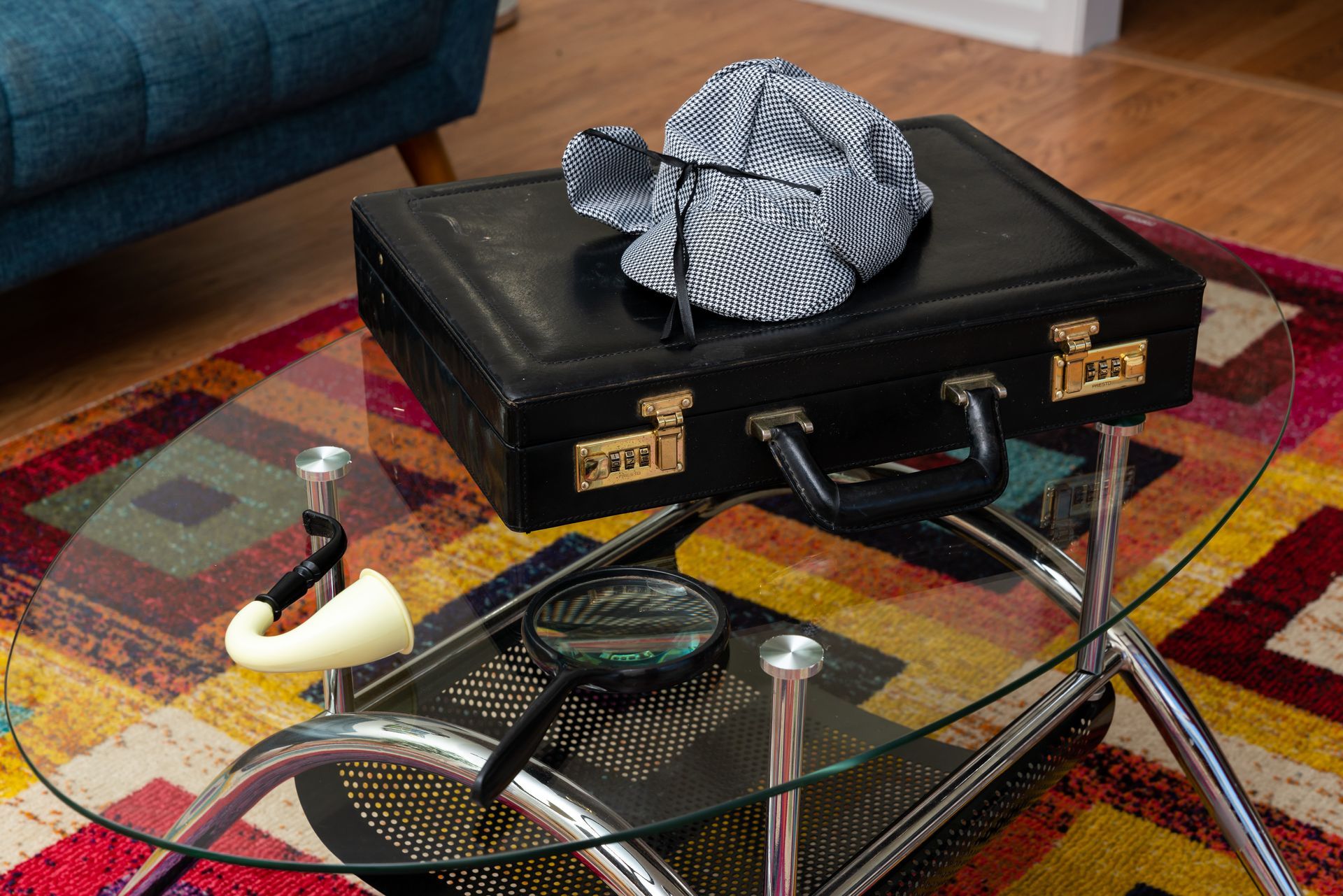 A detective hat is sitting on top of a briefcase on a glass table