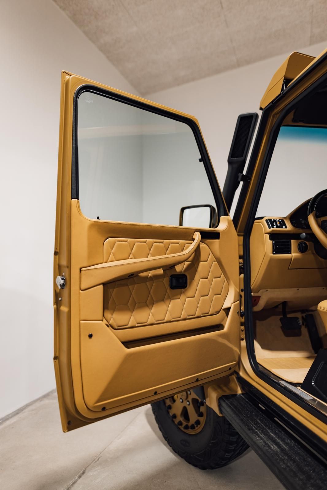 The door of a yellow car is open in a garage.