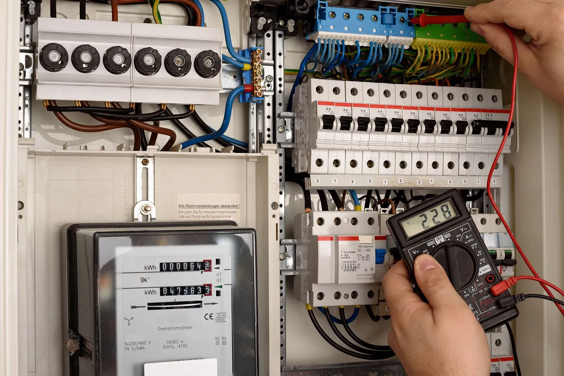 A person is using a multimeter to test an electrical box.
