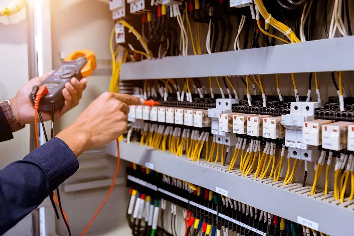 a man working on an electrical panel with a multimeter