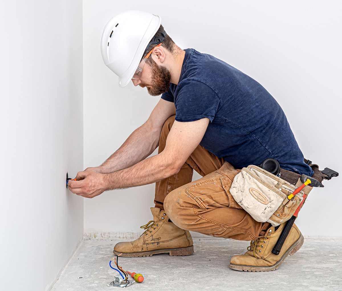 An electrician working on a wall.