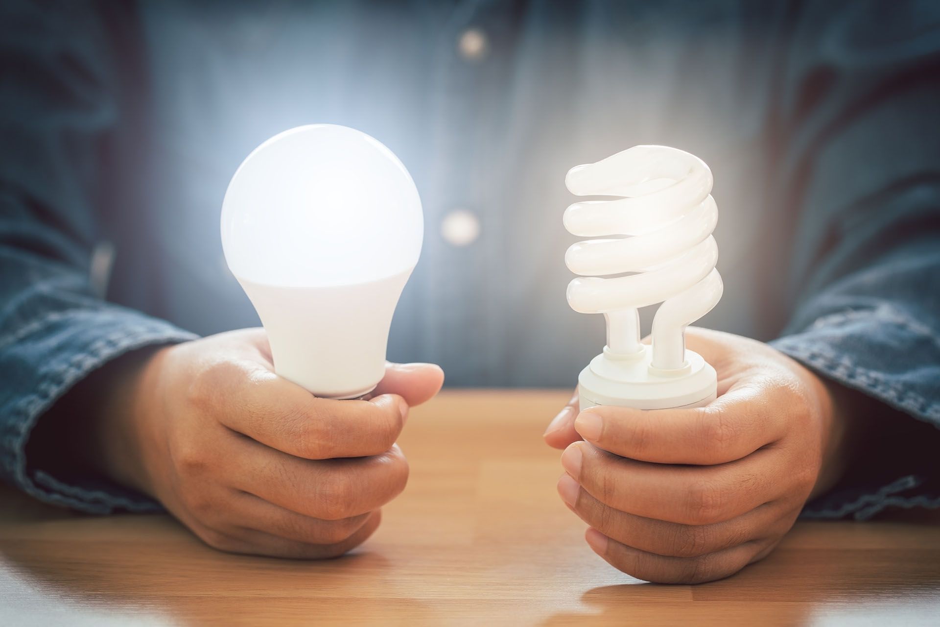 A person is holding two different types of light bulbs in their hands