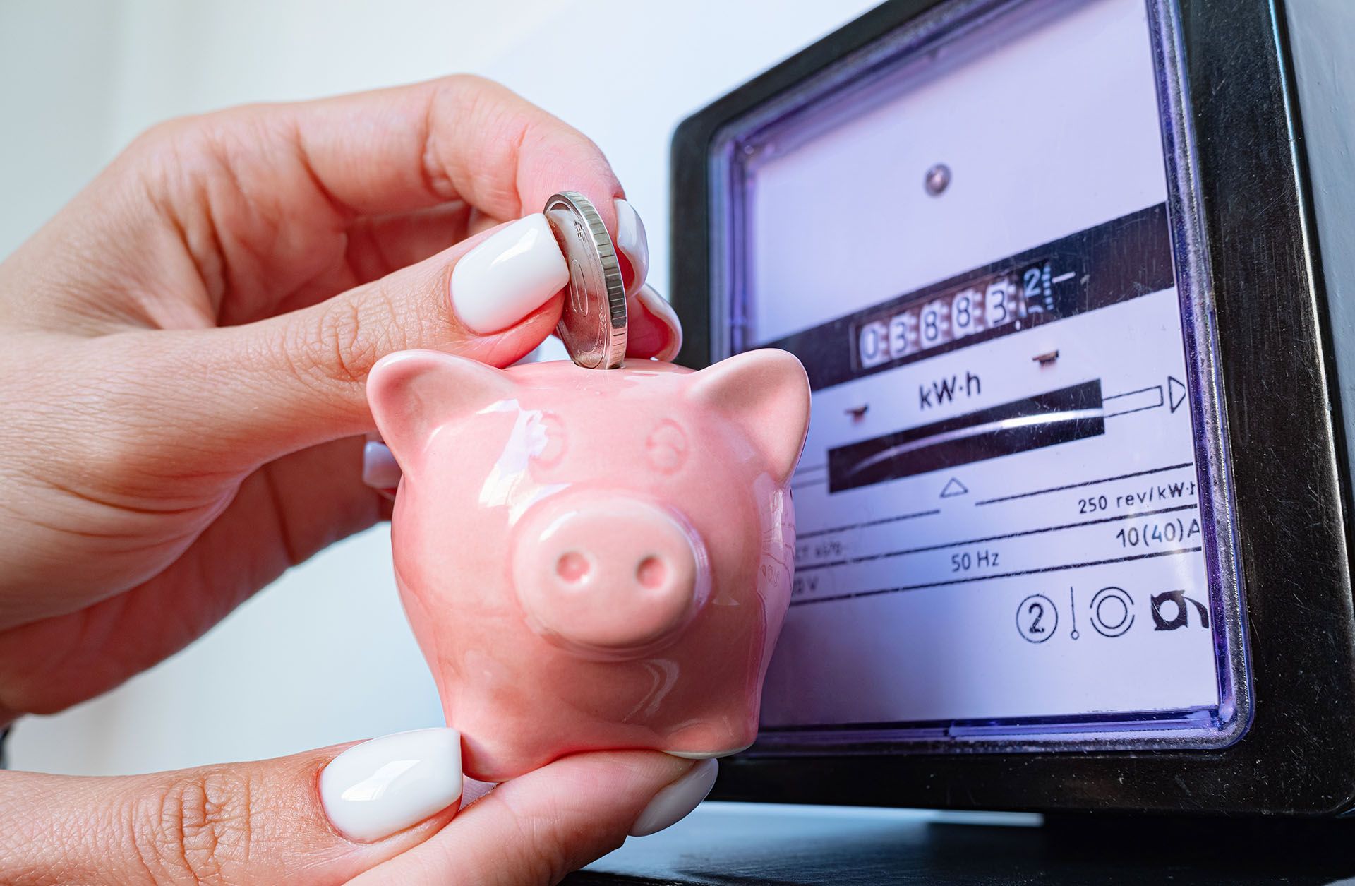 A woman is holding a pink piggy bank in front of a meter